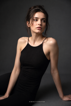 Woman with a messy bun wearing a black top against a dark background