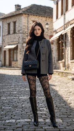 Woman in a grey jacket and lace tights on a cobblestone street