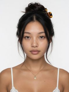Woman with a hair bun and gold necklace wearing a white lace-trim top