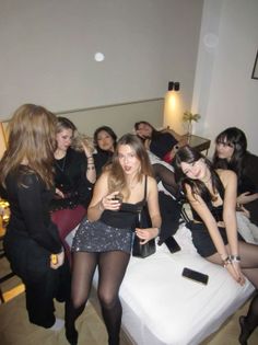 Group of women in a bedroom, some sitting on a bed, at night