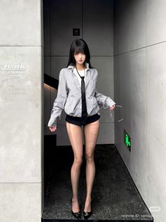 Woman in a striped shirt, black shorts, and sheer pantyhose posing indoors