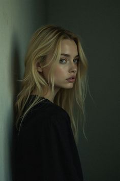 Blonde woman with long hair looking over her shoulder in soft indoor lighting