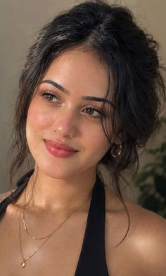 Woman with dark hair in an updo wearing a black halter top and gold jewelry