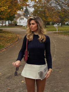 Woman with blonde hair wearing a sweater and mini skirt outdoors in autumn