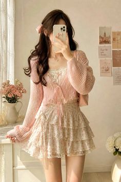 Woman in a pink cardigan and floral skirt taking a mirror selfie indoors
