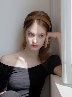 Woman with a brown headband and off-shoulder top in soft indoor lighting