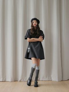 Woman in a black dress and beret with knee-high socks standing indoors
