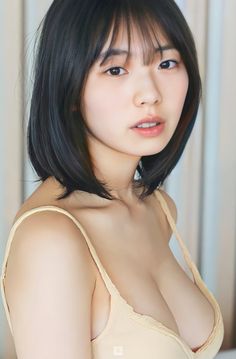 Woman with short black hair and bangs wearing a light-colored top