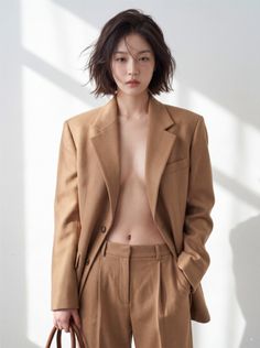 Woman with short hair wearing an open brown suit, posing indoors