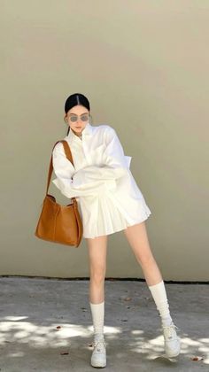 Woman in a white shirt dress and sunglasses posing outdoors