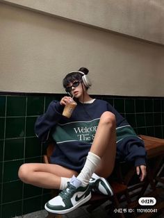 Woman in an oversized sweatshirt, sunglasses, and headphones, sitting indoors