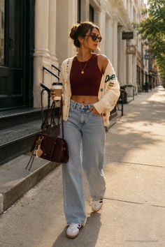 Woman in a crop top and loose jeans walking on a sunlit street