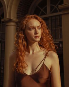 Woman with red curly hair and freckles in a brown top during golden hour