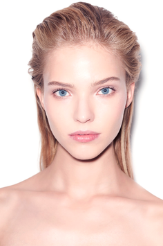 Woman with blonde wet hair and blue eyes against a white background