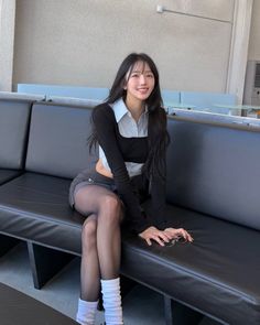 Woman with long black hair sitting on a black couch indoors
