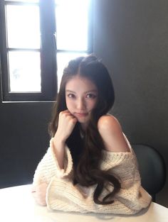 Woman with long hair wearing an off-shoulder sweater indoors with backlight