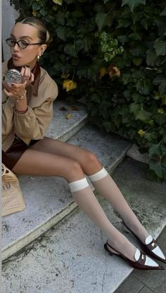 Woman in a brown skirt and knee-high socks sitting outdoors