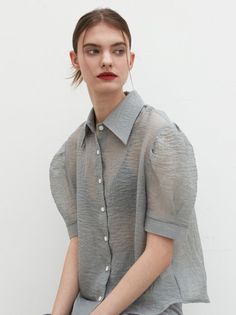 Woman in a sheer gray shirt and black bra with red lipstick
