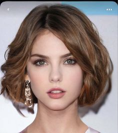 Woman with short brown hair and green eyes wearing earrings