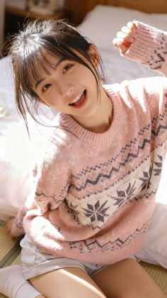 Woman in a pink fair isle sweater smiling indoors with soft lighting