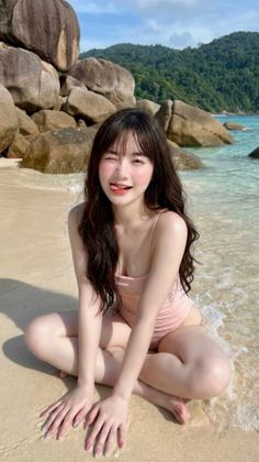 Woman in a pink swimsuit winking and sticking out her tongue on a beach