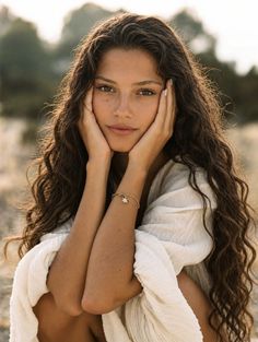 Woman with long curly hair wearing a white top outdoors