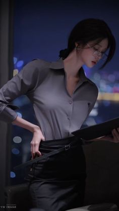 Woman in a grey shirt and black skirt with glasses, looking down at a document
