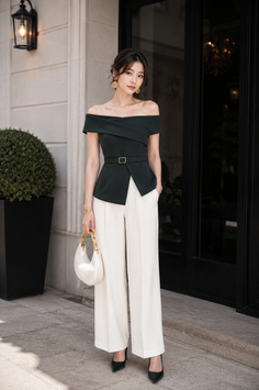 Woman in an off-shoulder top and wide-leg pants holding a white handbag outdoors