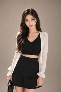 Woman with long hair wearing a black crop top and mini skirt with a white cardigan