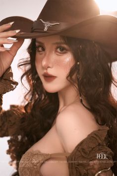 Woman in a cowboy hat and brown top with exposed shoulders and freckles