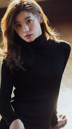 Woman in a black turtleneck with long hair, lit by warm backlight