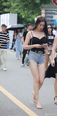 Woman in a black top and denim shorts walking on a street