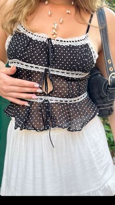 Woman wearing a sheer polka dot top with a white skirt and pearl necklace