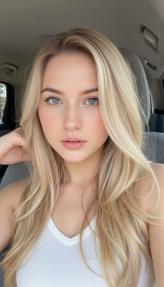 Blonde woman with blue eyes wearing a white top, captured in a soft-lit portrait
