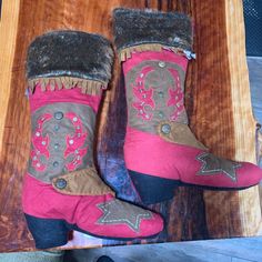 Pair of decorative Christmas stockings designed like cowboy boots on a wooden surface