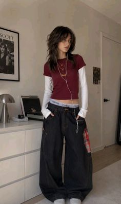 Woman with shaggy hair wearing a crop top and baggy jeans indoors