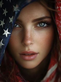 Close up portrait of a woman with blue eyes and freckles, partially covered by an American flag