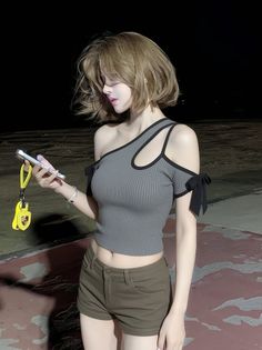 Woman with short hair wearing a crop top and shorts at night