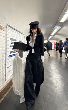 Woman in a black hat and wide leg pants in a subway station