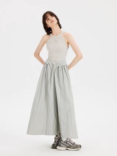 Woman with short hair wearing a sleeveless top and long skirt with sneakers