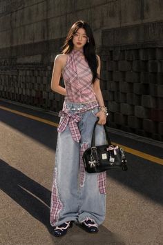 Woman in a plaid top and wide leg jeans standing on a street