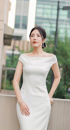 Woman in a white off-shoulder dress with an updo and jewelry outdoors