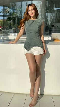 Woman with long hair wearing a denim top and white shorts outdoors