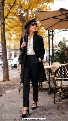 Woman in a black coat and beret walking past an outdoor cafe