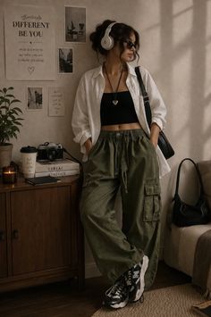 Woman in cargo pants, white shirt, and crop top with headphones indoors