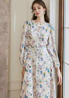 Woman in a floral dress with long sleeves and pearl earrings indoors