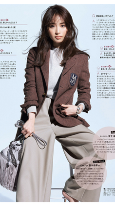 Woman in a brown blazer and wide leg pants holding a fringe bag