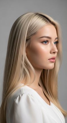 Woman with long blonde hair and blue eyes in a white shirt, looking to the side