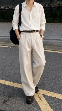Person in a white shirt and wide leg pants with a black backpack on a street