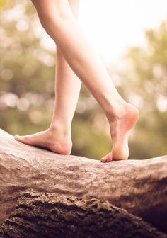 Bare feet walking on a tree trunk with soft lighting
